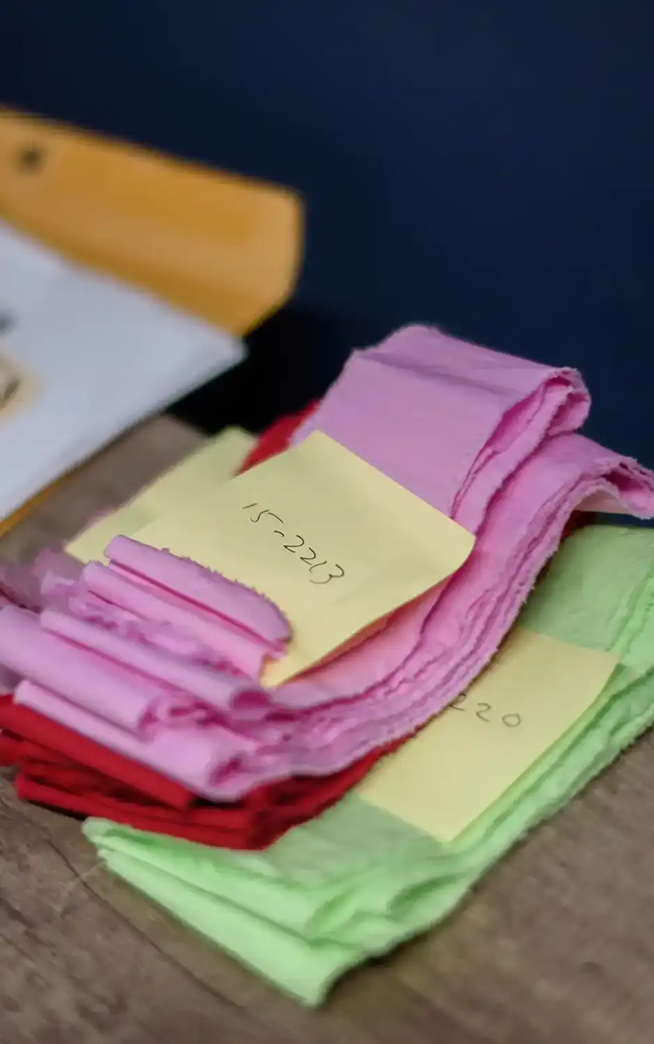 Samples of fabrics that were dyed pink, red, and green on a table